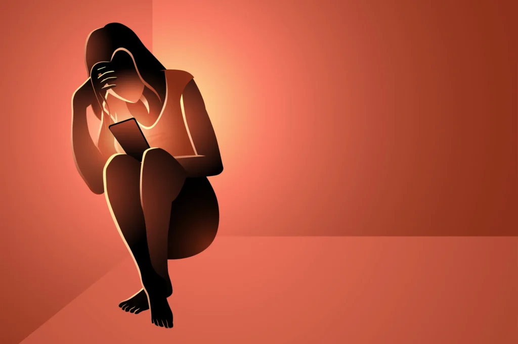 A stylized illustration of a distraught woman crouching, holding a glowing smartphone, with her hand covering part of her face, against a warm, gradient background. The image evokes feelings of distress, cyberbullying, or the negative impact of online content, reflecting the themes of exploitation and harm discussed in the article on AI-generated pornography.