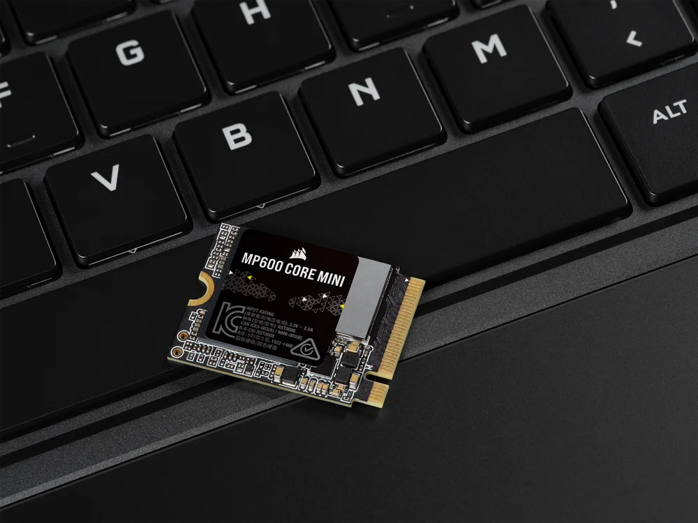A Corsair MP600 CORE MINI M.2 SSD resting on a black laptop keyboard, highlighting its compact size and advanced technology for high-performance storage.